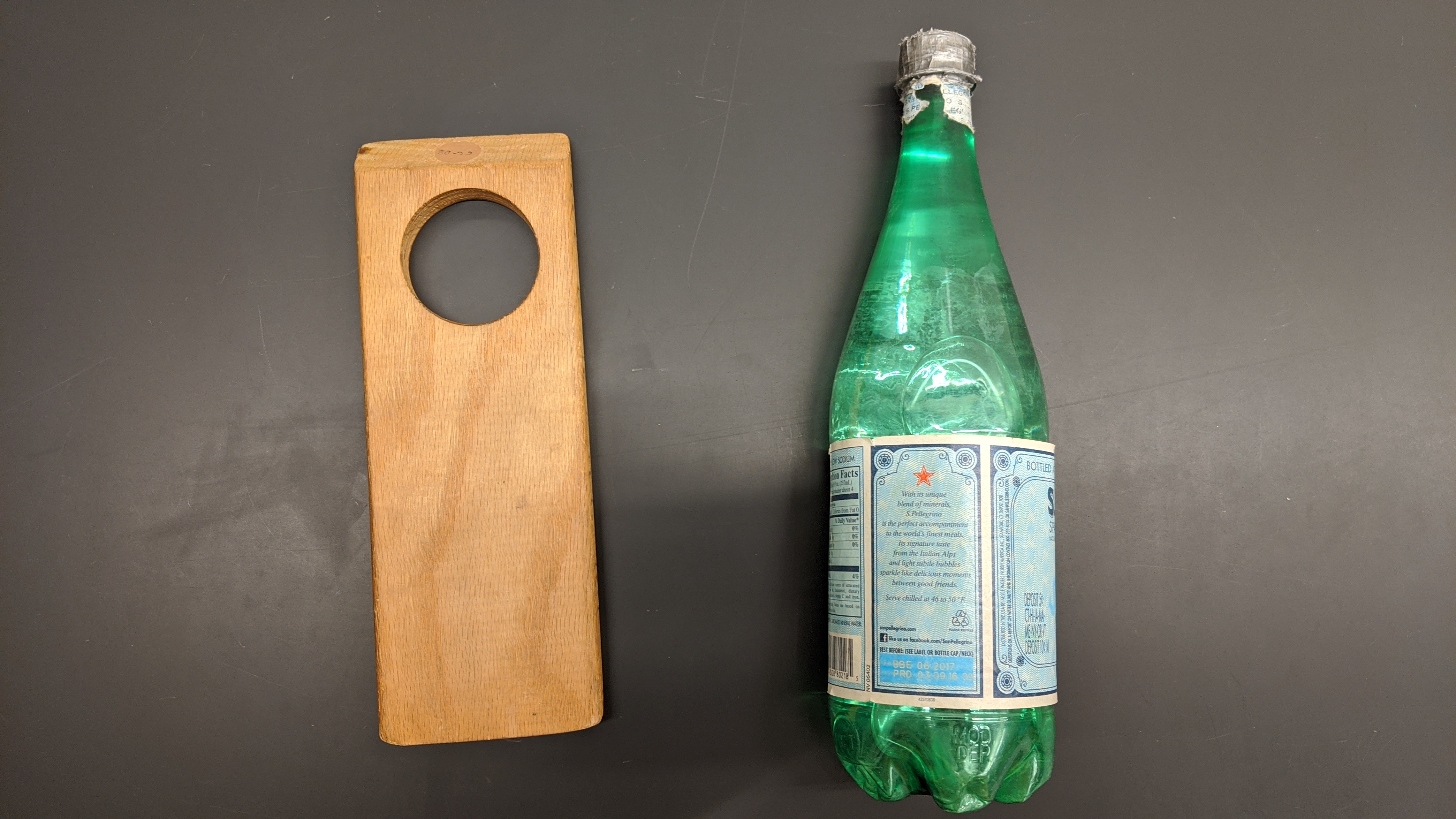 A bottle of water, and a piece of wood with a hole in it