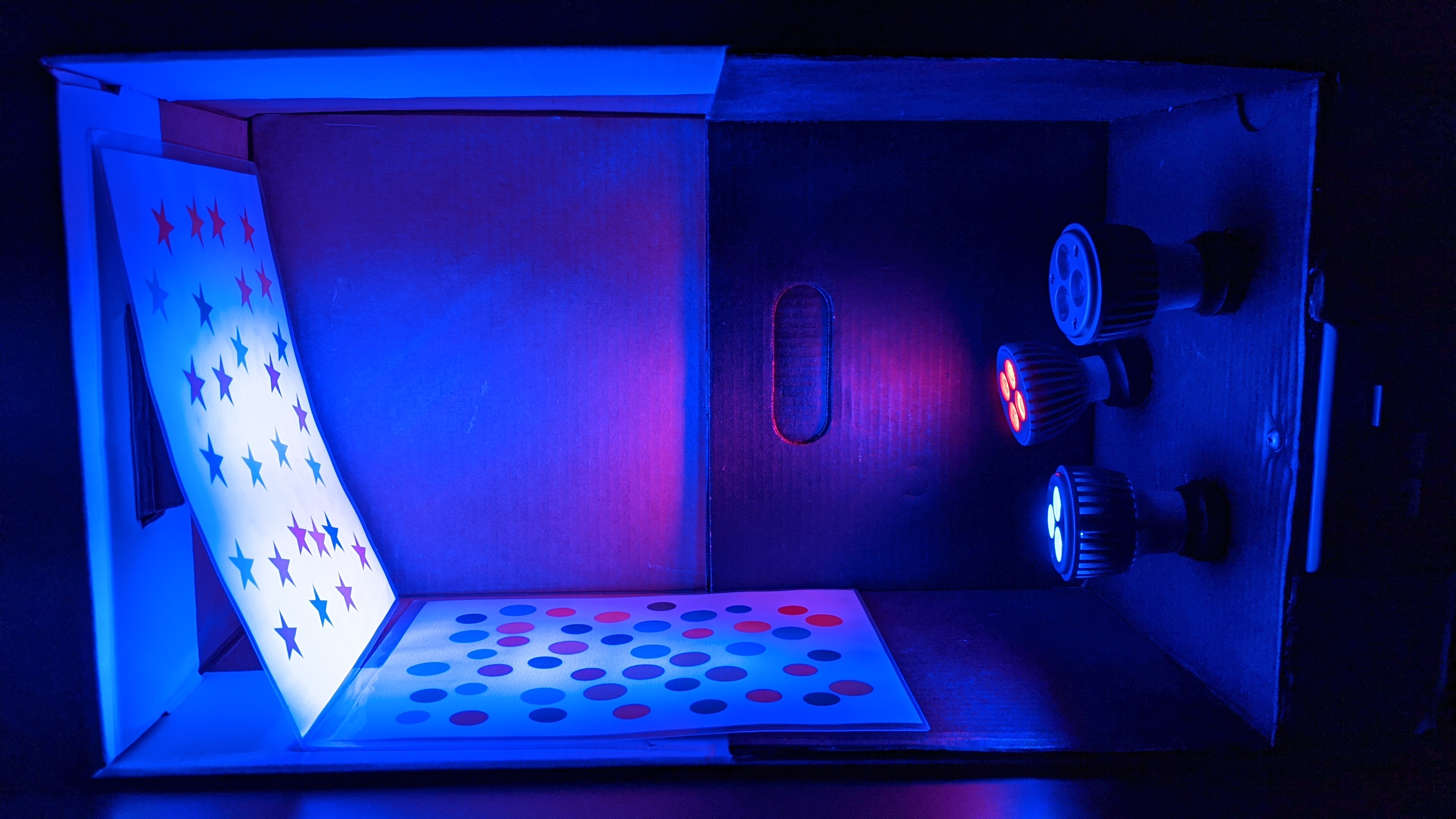 A box with red, green, and blue light bulbs, switches to turn each on or off individually, and sheets with colored stars and circles