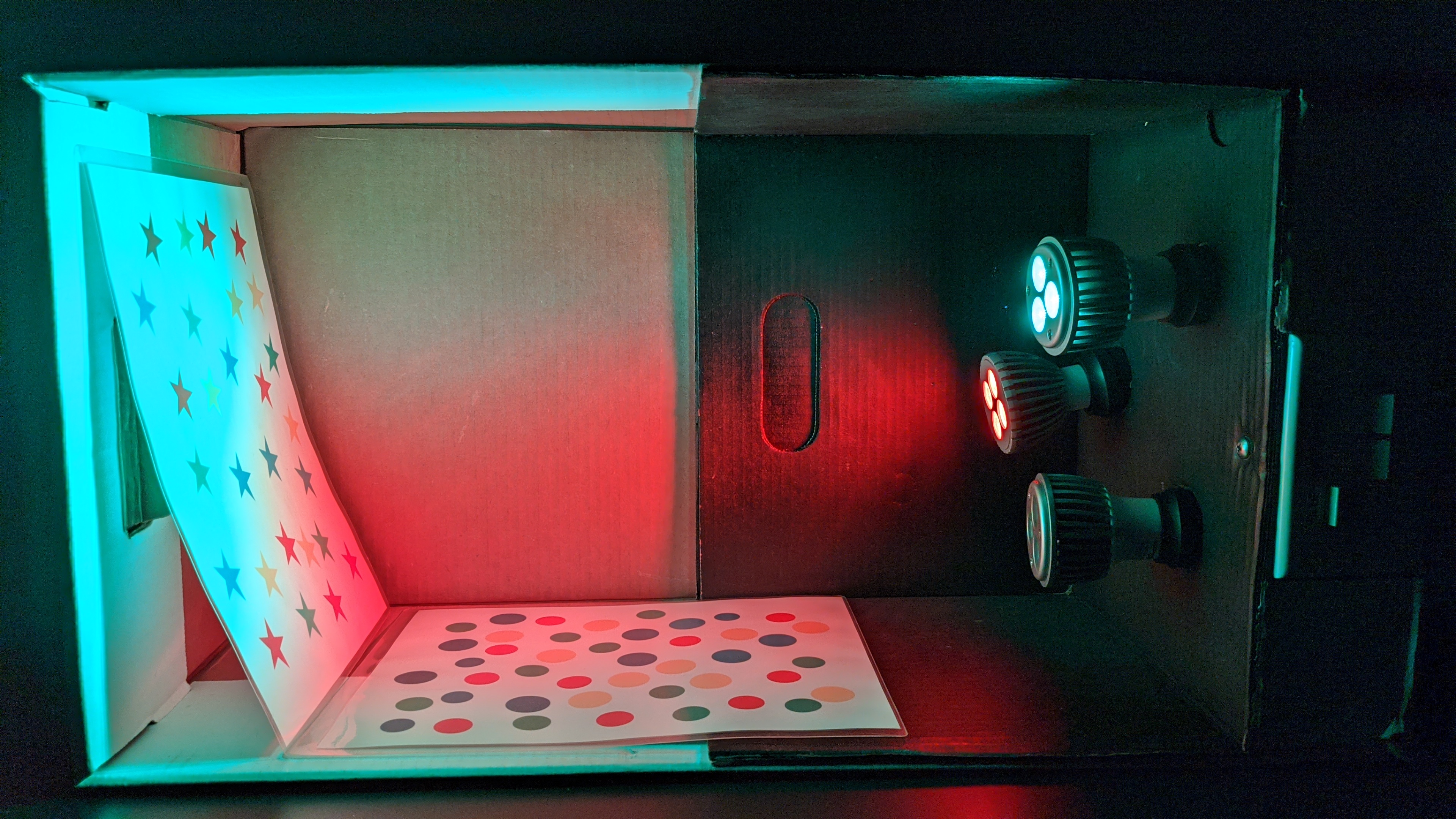 A box with red, green, and blue light bulbs, switches to turn each on or off individually, and sheets with colored stars and circles