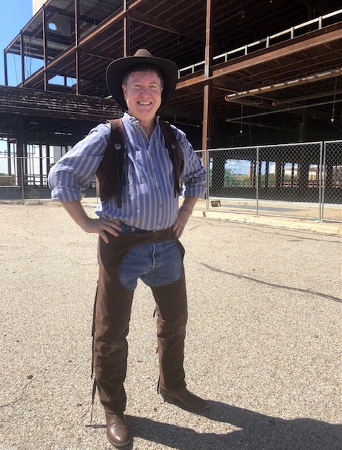 Dr. Cook wearing a cowboy hat in front of new ACC Highland Construction
