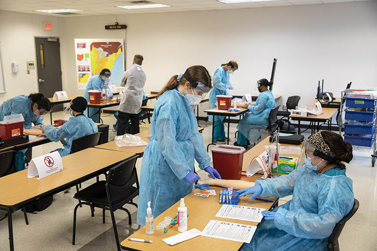 Students practice drawing blood during a phlebotomy class. 