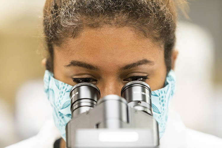 A Medical Lab Technology student looks through a microscope. 