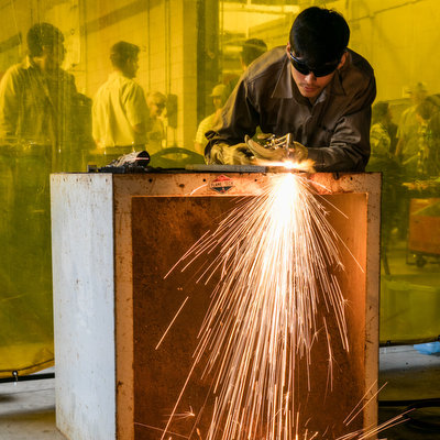 ACC student welding with sparks flying.