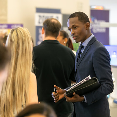 Person in a suit holding a tablet in a business setting.