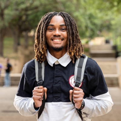 Austin Community College | Austin Community College District Antoine, a young black man with dreadlocks wearing a blue and white polo shirt and carrying a backpack, smiles at the camera. Antoine is a Bats to Cats transfer student.