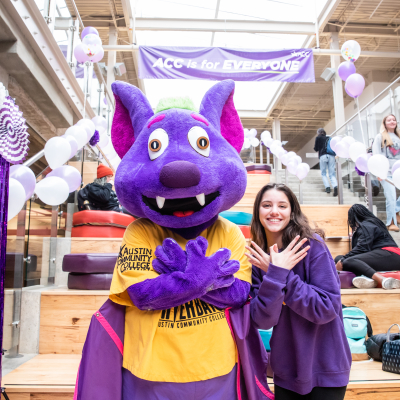 Austin Community College | Austin Community College District ACC mascot RB the Riverbat, a purple and gold bat, poses with a student