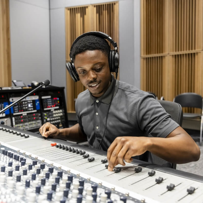 Person in a recording studio adjusting audio equipment.