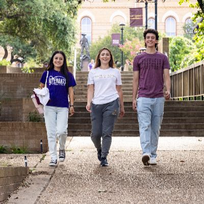 Lockhart Center | Austin Community College District ACC transfer students walking down the steps of a university building, engaged in conversation and carrying backpacks.