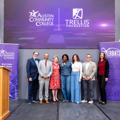 ACC Chancellor Russel Lowry-Hart stands with representatives from ACC and the Trellis Foundation in front of a purple banner showcasing ACC and Trellis and the ACC Riverbats